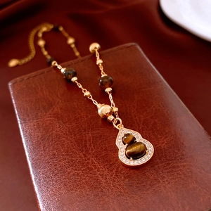 Detail of tiger eye bead necklace with gourd pendant and sparkling zircon accents