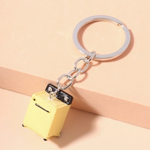 Close-up of a miniature yellow multicooker keychain on a minimalist geometric background