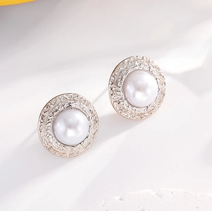 Macro shot of pearl stud earrings featuring textured silver bezels and white pearls