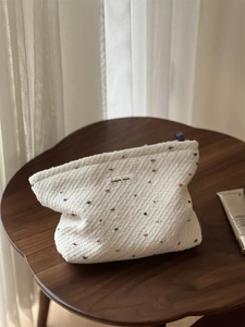 Detail of simple wish label on cream tweed makeup bag with colorful polka dots