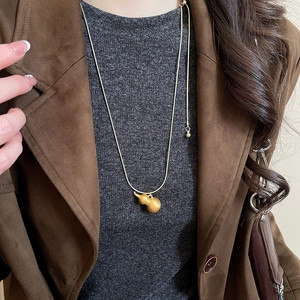 Collana con ciondolo a doppia zucca dorata indossata con giacca scamosciata marrone