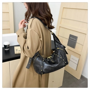 Detail view of retro black rivet shoulder bag with metal studs and tassel on female model