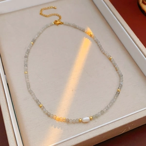 Detail shot of a grey gemstone beaded necklace with a white freshwater pearl centerpiece