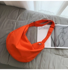 Detailed shot of an orange crescent oxford cloth bag with adjustable shoulder strap and zipper