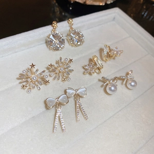 Ensemble détaillé de boucles d'oreilles dorées avec zircon, perles, nœuds et fleurs