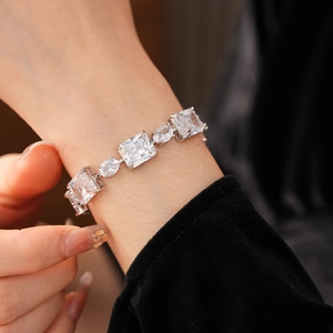 Close-up of a silver bracelet featuring alternating rectangular and oval clear crystals