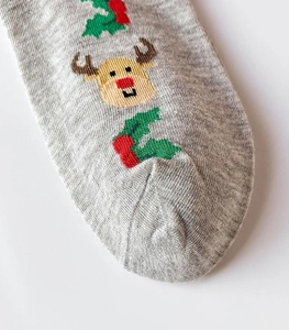 Close-up of grey knit Christmas socks featuring festive elk and holly embroidery details