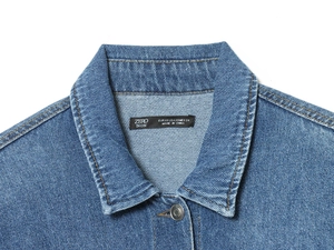 Detail of blue denim jacket collar with buttons and XS size label on white background