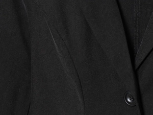 Macro shot of black blazer twill fabric texture with a single polished black button detail