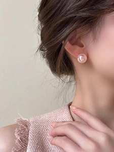 Macro shot of elegant pink pearl stud earring with glossy metallic finish on ear