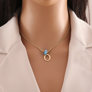 Detail of gold evil eye pendant with letter O on a twisted chain necklace for women
