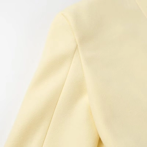 Macro detail showing the high-quality stitching and woven texture of the yellow wool coat