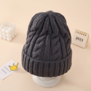 Detail of dark grey cable knit beanie showing thick wool texture and folded cuff