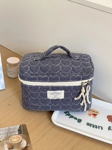 Detail of blue heart-quilted gingham makeup bag with soft fabric handle and zipper cord