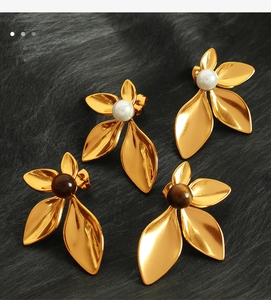 Detailed view of 18K gold flower earrings with white pearls and brown agate on fur