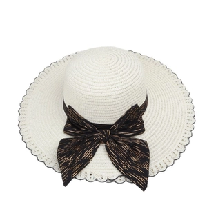 White straw sun hat with large wavy brim and black bow ribbon for beach vacation