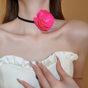 Close-up of a large magenta fabric flower choker with a minimalist black lace strap