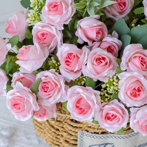 Detail of decorative pink silk roses in a woven basket with handle for home floral decor