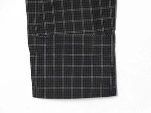 Detailed close-up of dark grey plaid fabric with precise double-needle stitching on cuff