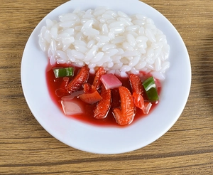 Macro view of realistic miniature PVC rice bowl model with sauce on wooden surface
