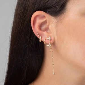 Close-up of gold butterfly tassel earrings and zircon hoops on a female model