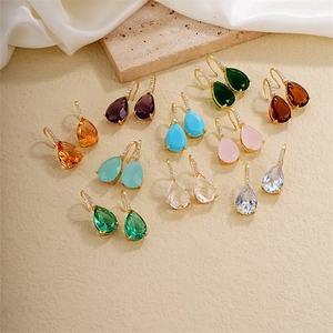 Detailed view of teardrop zircon earrings in various colors on a stone base