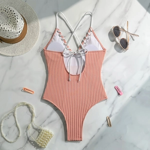 Detail of pink ribbed swimsuit featuring cross straps and white lace-up back design