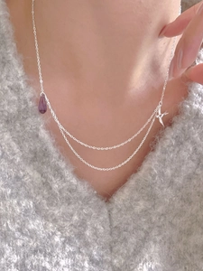 Close-up of double-layer silver necklace featuring purple droplet and swallow pendants
