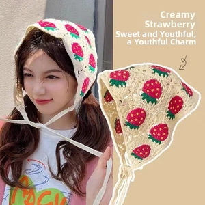 Detail of beige crochet triangle headscarf with red strawberry embroidery and tie straps