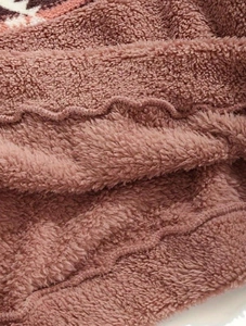 Dettaglio del morbido tessuto in pile sherpa rosa con trama calda e cuciture