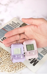 Miniature handheld arcade console keychains in purple and pink with joystick and buttons