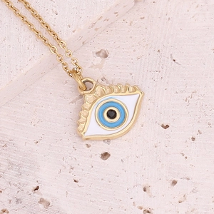 Macro shot of gold evil eye pendant with blue and white enamel on a stone surface