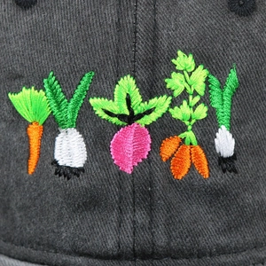 Macro detail of vibrant vegetable embroidery on dark grey washed cotton baseball cap