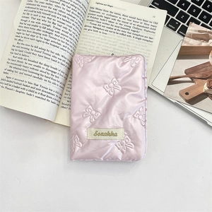 Detail of pink quilted bow storage case for passport and travel documents on a vintage book