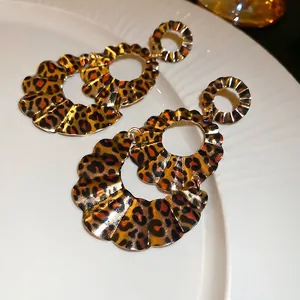 Leopard print layered earrings with wavy edges and vintage style on white textured plate