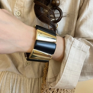 Macro detail of minimalist acrylic and gold metal elastic bracelet on model's wrist