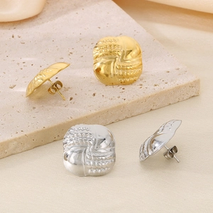 Detail of round vintage earrings with embossed woven texture in gold and silver finish