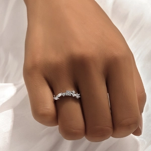 Close-up of S925 sterling silver ring with crystals on finger against white cloth