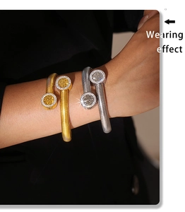 Detail view of tree of life charm bangles with crystals on model in gold and silver