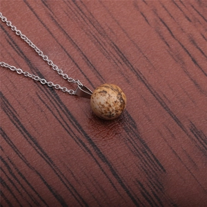 Detailed close-up of a round brown stone pendant on a silver chain necklace