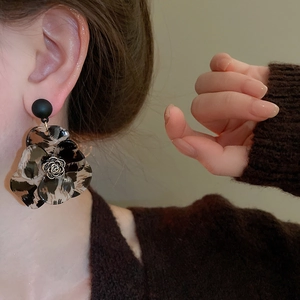 Close-up of C-shaped floral earrings with leopard resin petals and golden rose center
