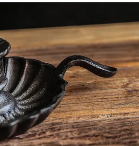 Close-up of vintage black cast iron shell candle holder with ergonomic handle design