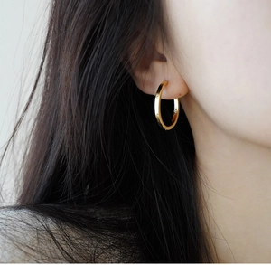 Close-up of a model wearing a minimalist gold sterling silver hoop earring with polished finish