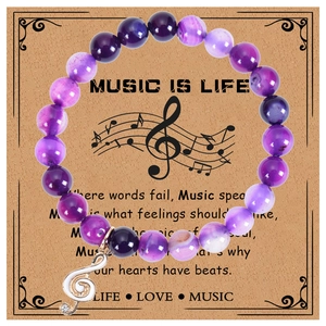 Gros plan détaillé d'un bracelet de musique en pierre naturelle violette de 8 mm avec breloque
