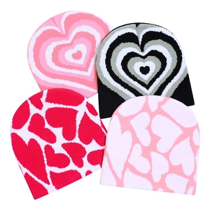 Winter knitted beanies with heart patterns in pink, black, and red colors