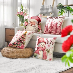 Detail of four pink Christmas pillow covers with Santa and trees on a cozy sofa