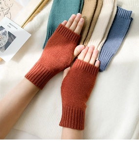 Detail of soft knit fingerless gloves in rust red showing warm wool texture and style