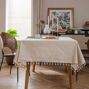 Detail of beige cotton linen tablecloth with white dots and elegant tassel fringe