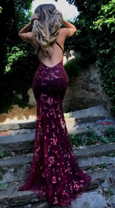 Detail of the backless slim fit evening gown in deep red sequins with floor-length hem