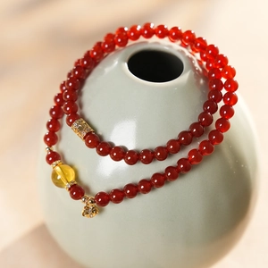 Détail d'un bracelet double couche en agate rouge avec breloque fleur dorée sur vase